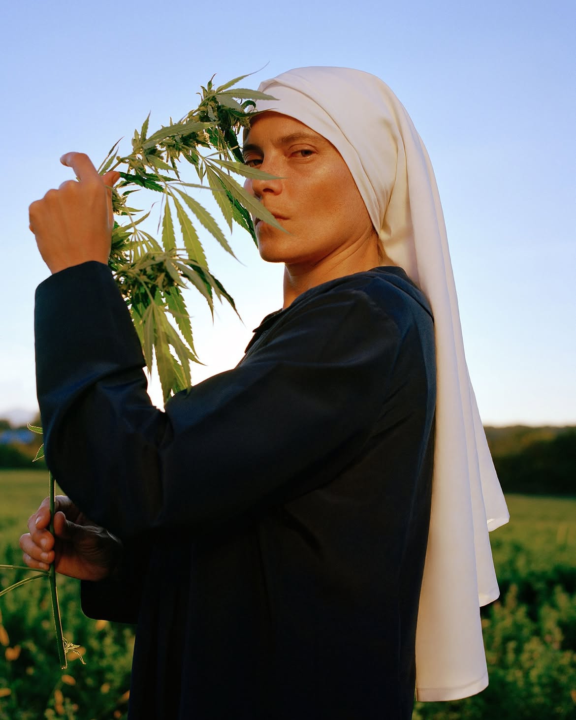 A Sister standing outdoors with a cannabis plant